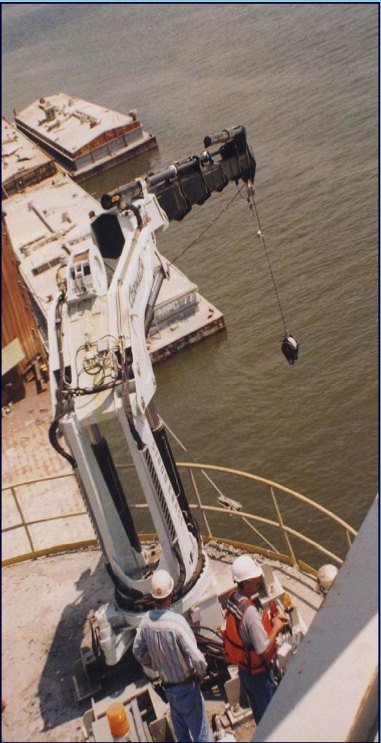 Marine crane working from a barge deck with the crew below